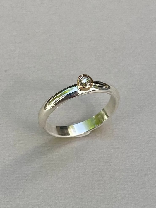 Silver ring with a small diamond on a light gray background